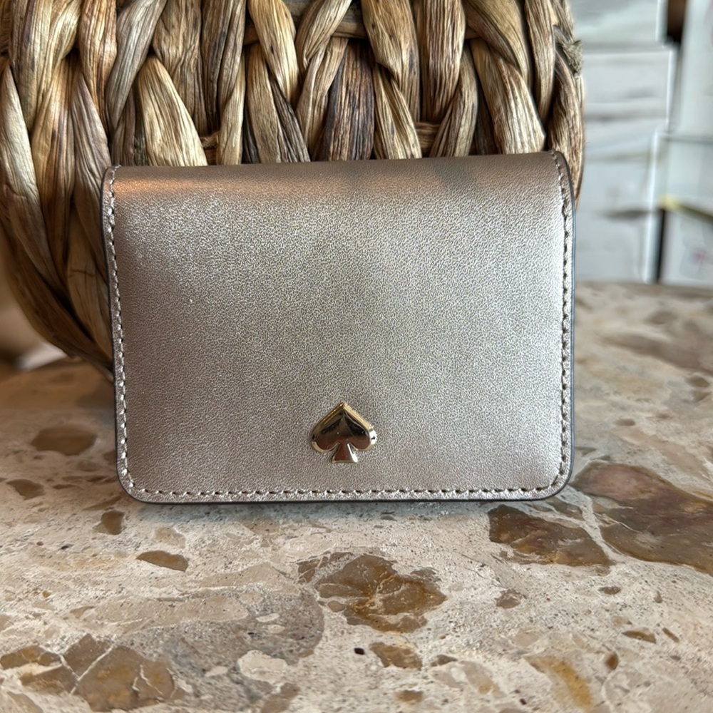 Kate Spade slim bifold card holder in gold leather. Measures 4“ x 3“